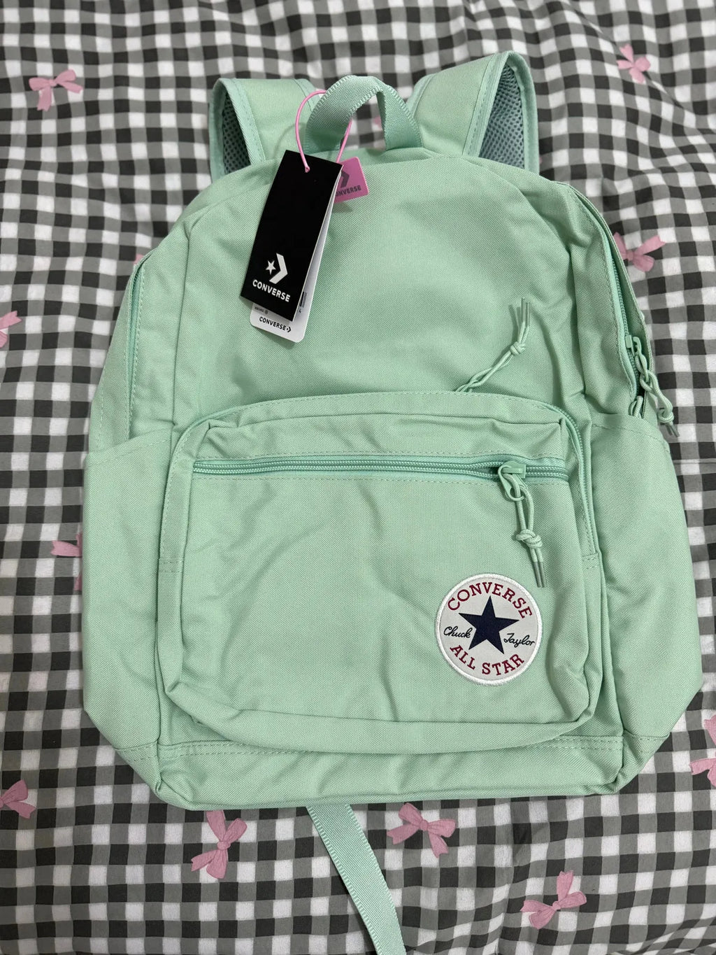 Light green Converse backpack with a tag on a checkered background
