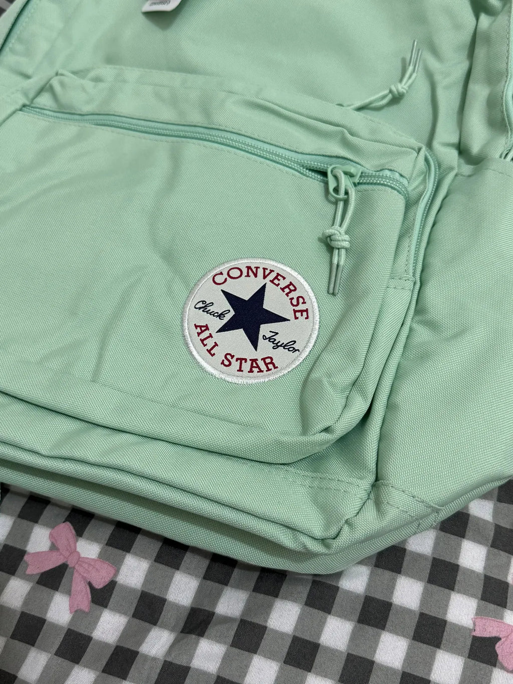 Light green backpack with Converse All Star logo on a checkered background