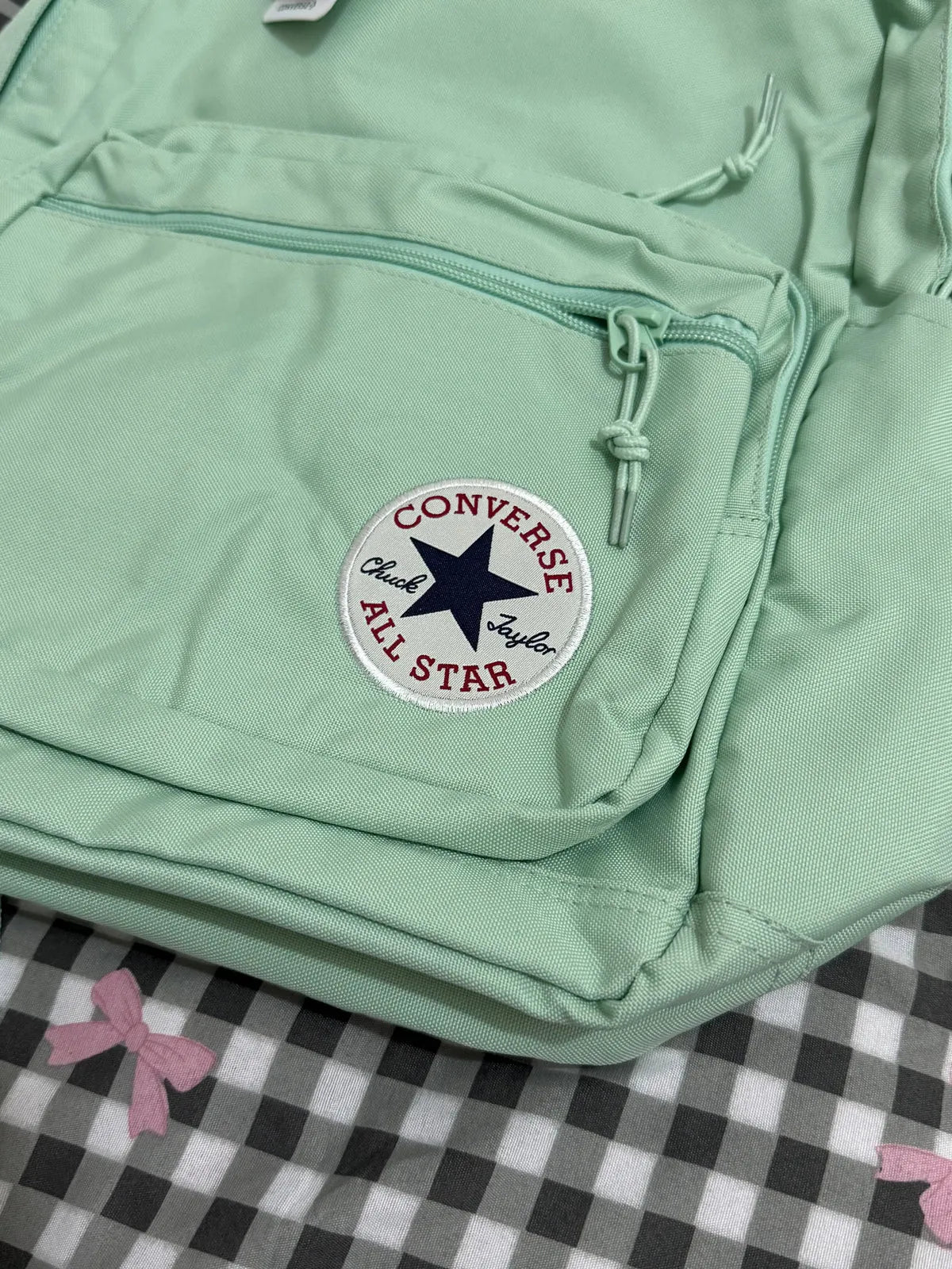 Light green backpack with Converse All Star logo on a checkered background