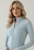 Woman wearing a light blue athletic jacket against a plain background
