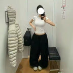 Person taking a mirror selfie wearing a white top and black pants in a fitting room.