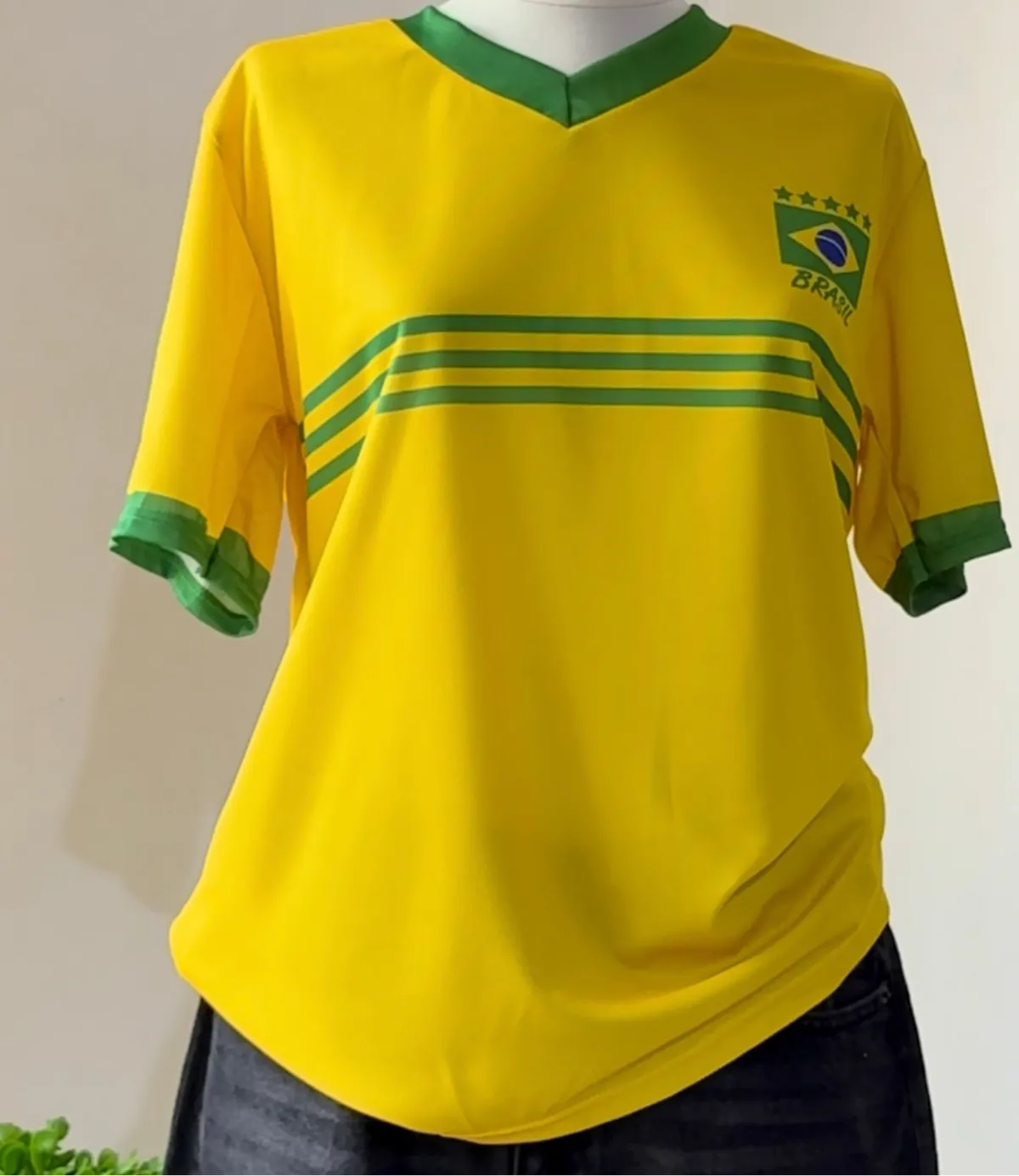Yellow sports jersey with green accents on a mannequin against a neutral background