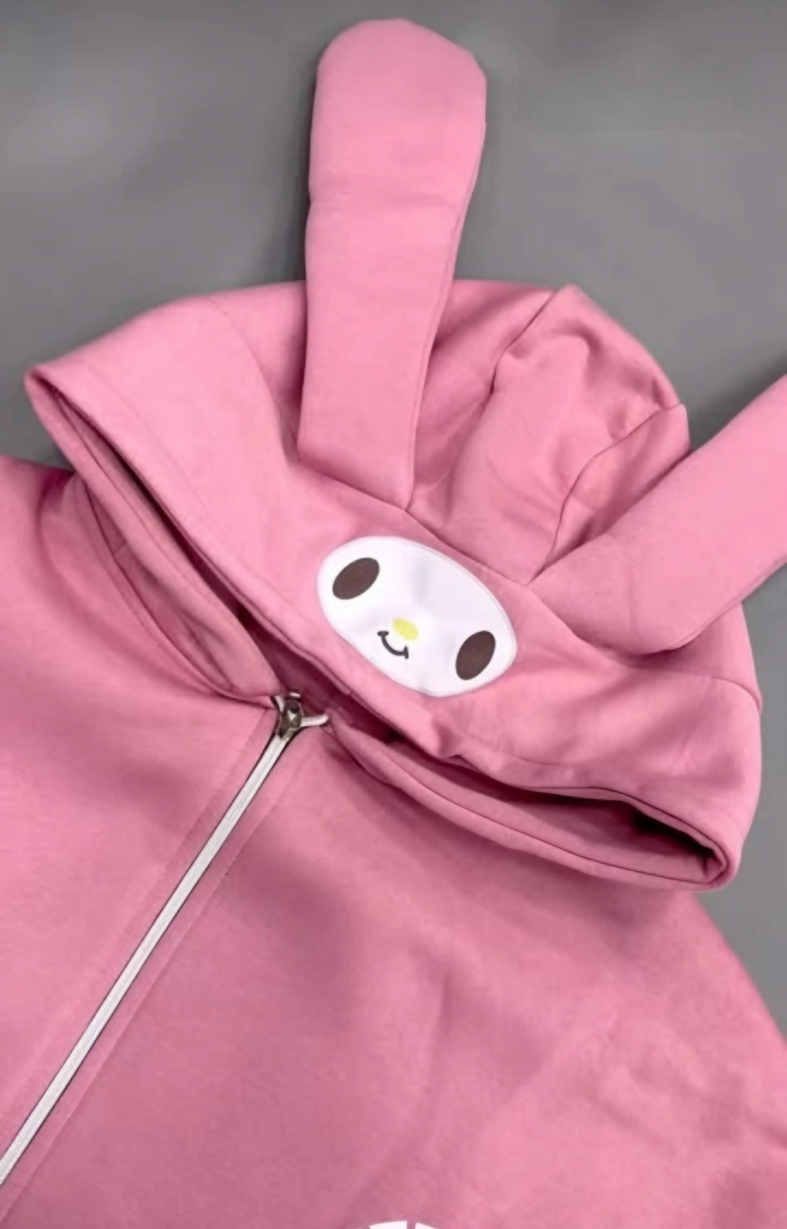Pink jacket with a cartoon face design on a gray background