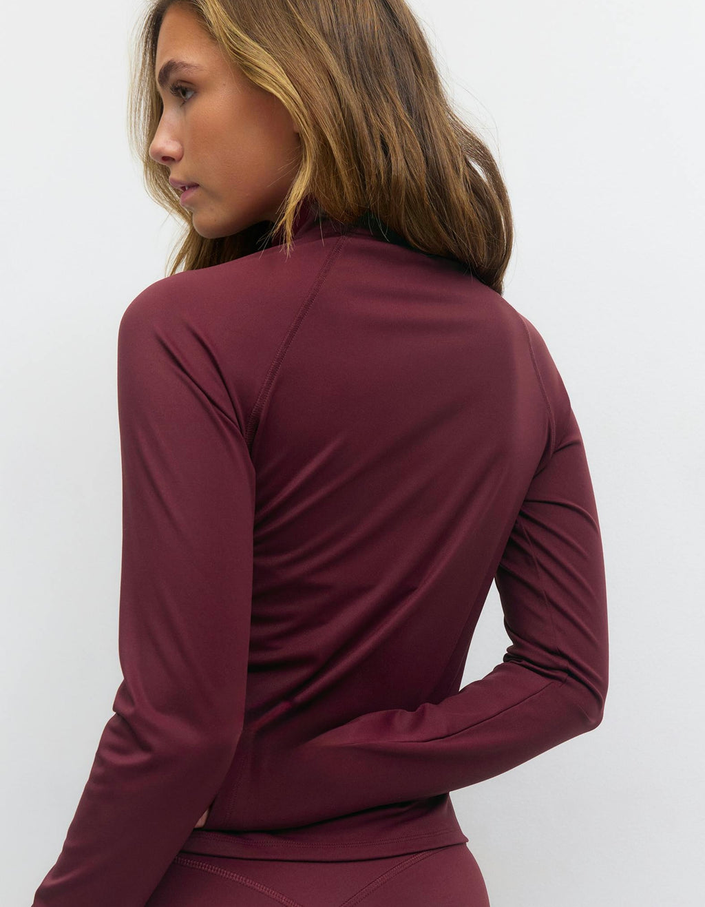 Maroon long-sleeve top worn by a person on a white background