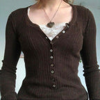 Brown ribbed cardigan over a white lace top on a plain background