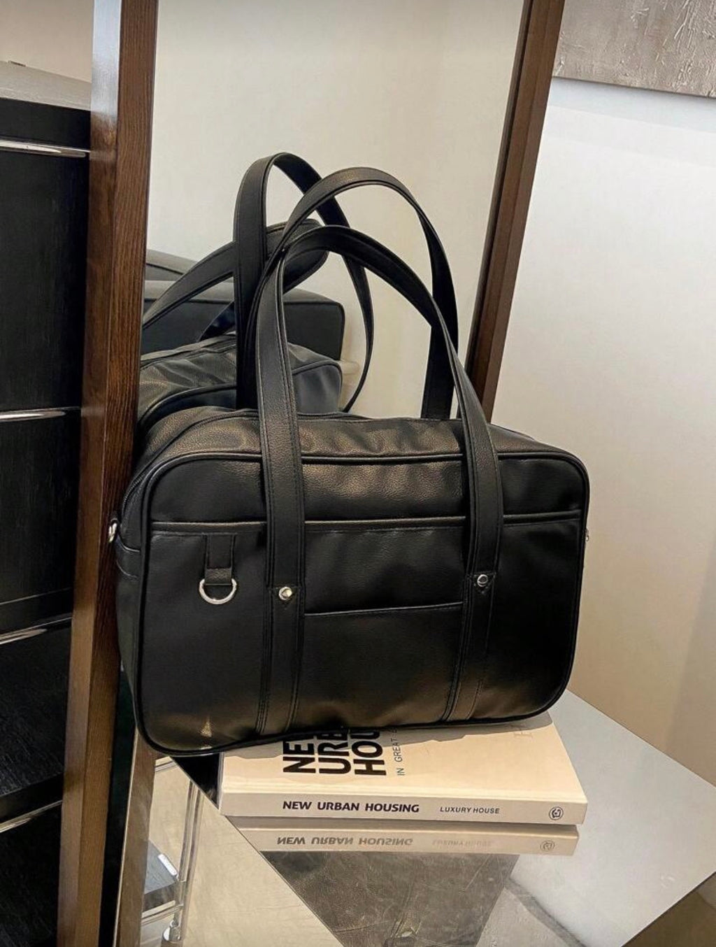 Black leather duffel bag on a book with a blurred background