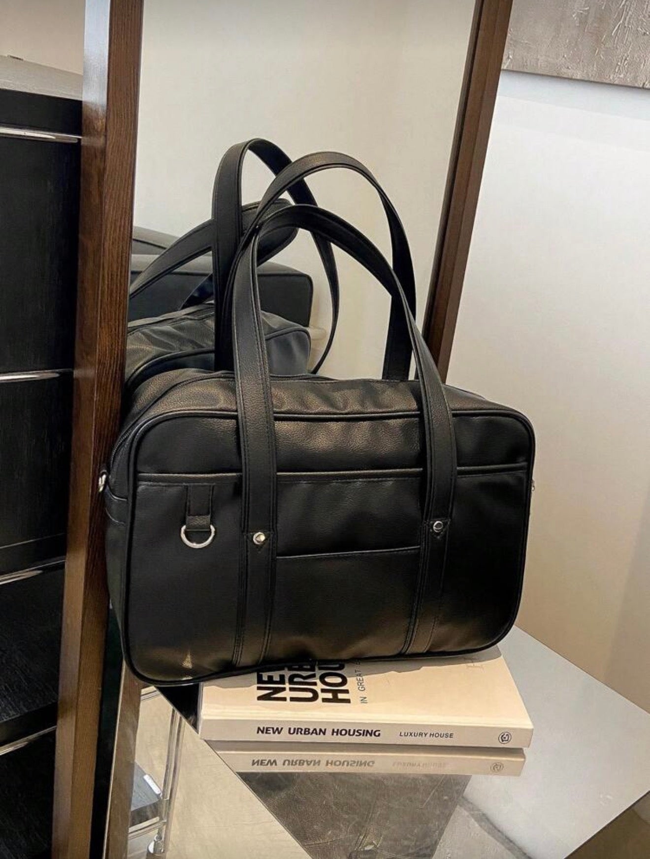 Black leather duffel bag on a book with a blurred background