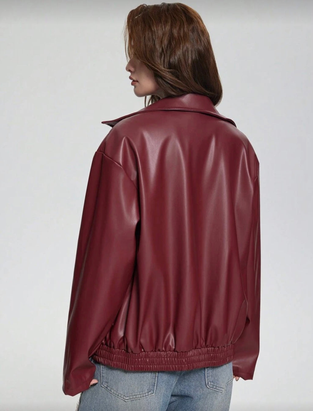 Person wearing a maroon leather jacket on a plain background