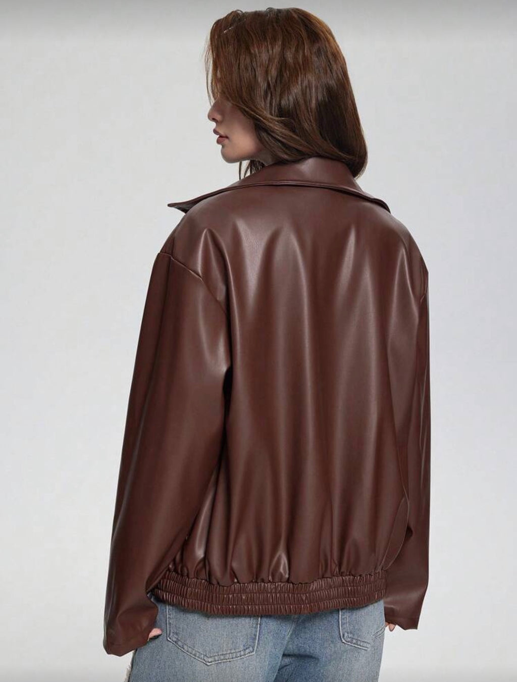 Person wearing a brown leather jacket on a plain background