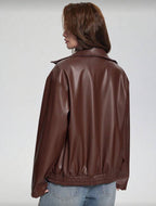 Person wearing a brown leather jacket on a plain background