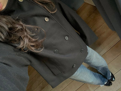 Person wearing a dark coat and light blue jeans on a wooden floor