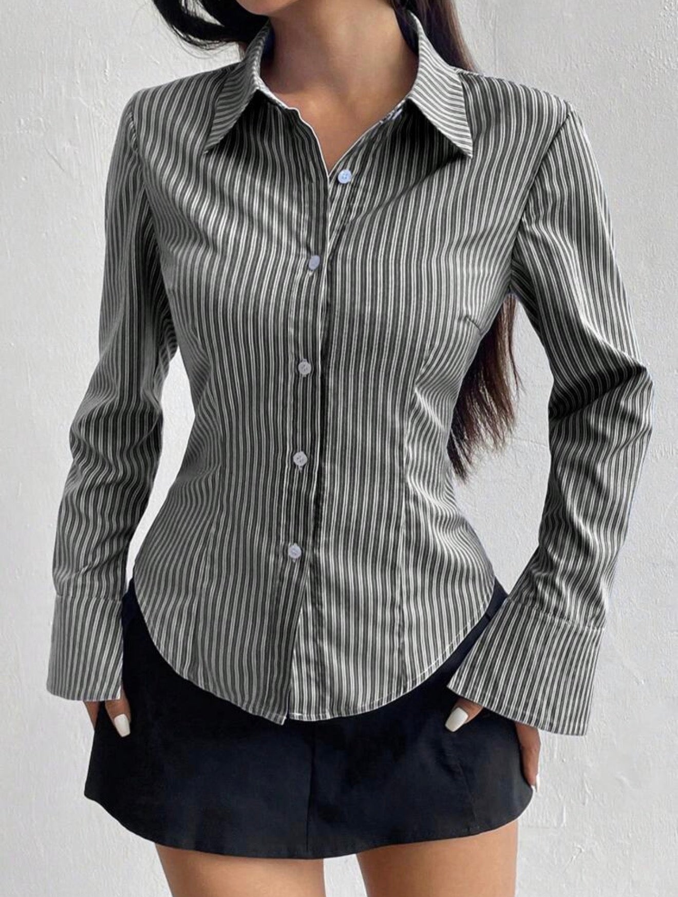 Person wearing a gray and white striped shirt with a plain background