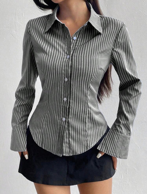 Person wearing a gray and white striped shirt with a plain background