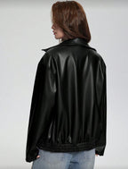 Person wearing a black leather jacket on a plain background