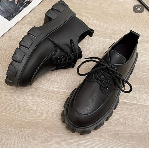 Pair of black leather shoes on a wooden surface