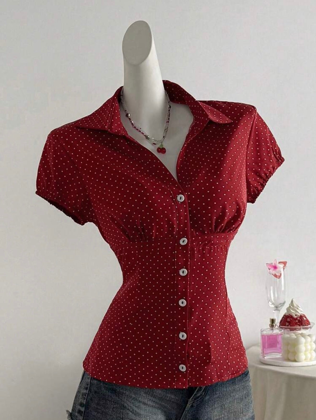 Red polka dot shirt on a mannequin against a plain background