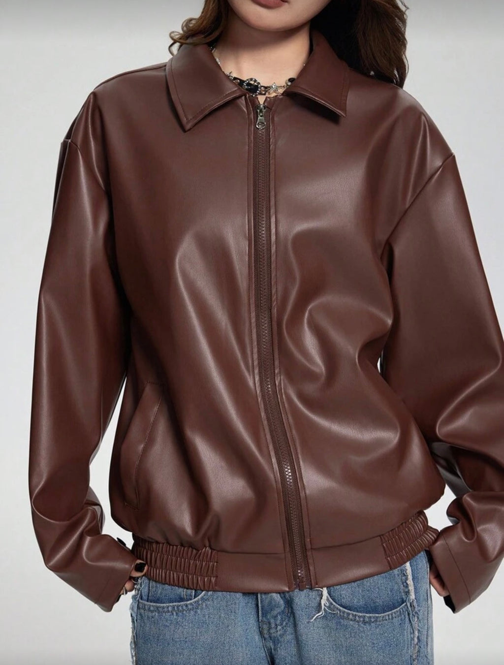 Brown leather jacket worn by a person on a plain background