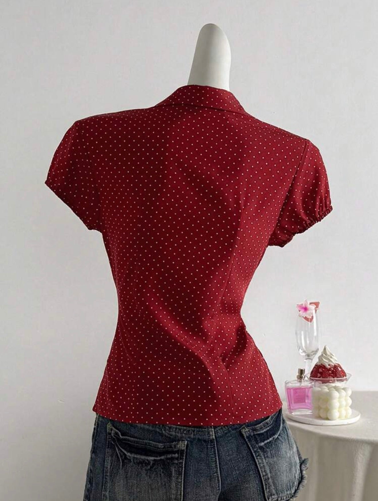 Red polka dot top on a mannequin against a plain background