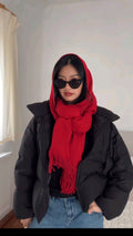 Person wearing a red scarf and black coat indoors