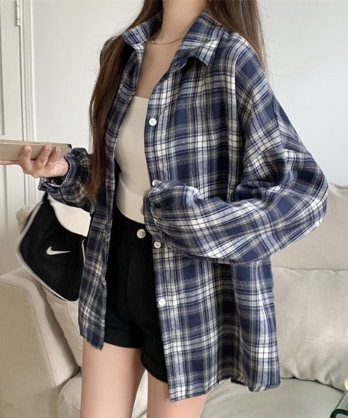 Person wearing a blue plaid shirt in a casual indoor setting