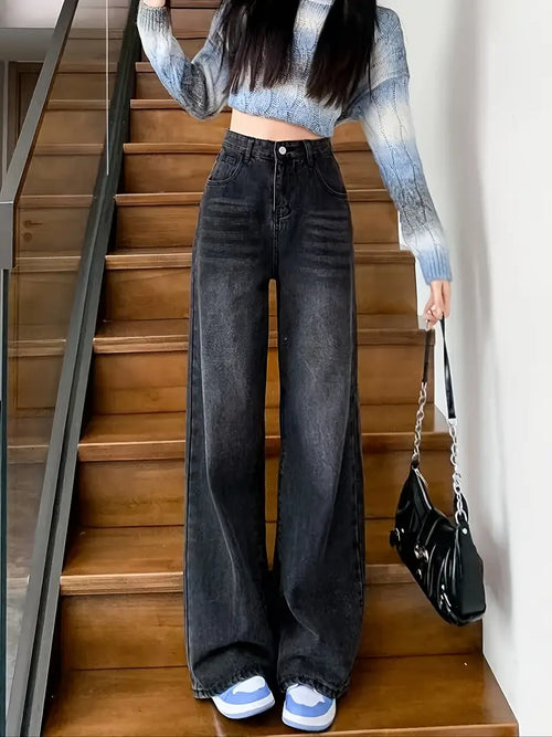 Person wearing a striped sweater and wide-leg jeans standing on wooden stairs.