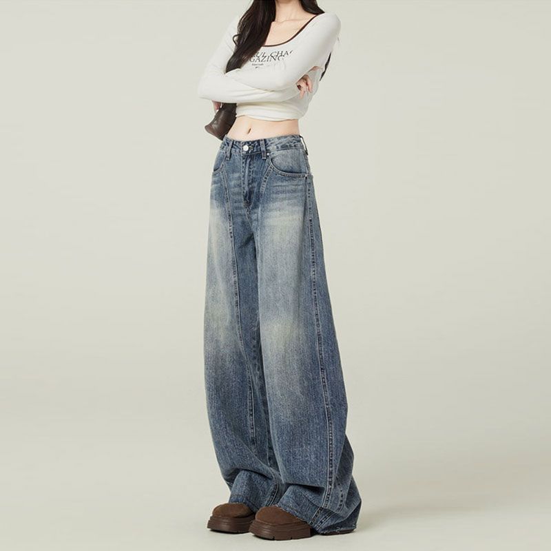 Person wearing wide-leg jeans and a white crop top on a plain background