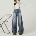 Person wearing high-waisted blue jeans and a white crop top on a plain background