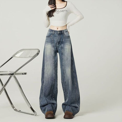 Person wearing high-waisted blue jeans and a white crop top on a plain background