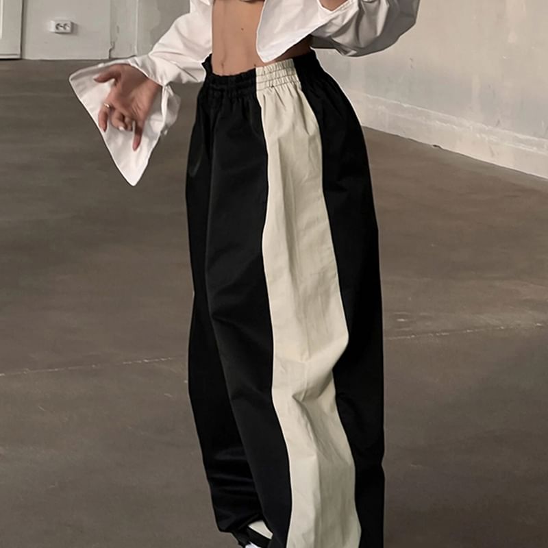 Person wearing a white shirt and black and white striped pants in an indoor setting.