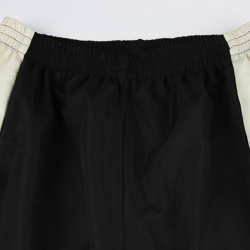Black pants with a white waistband on a light gray background