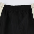 Black pants with a white waistband on a light gray background