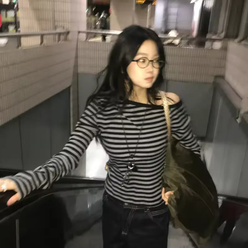 Woman in a striped shirt and glasses standing in an indoor setting black and white striped shirt