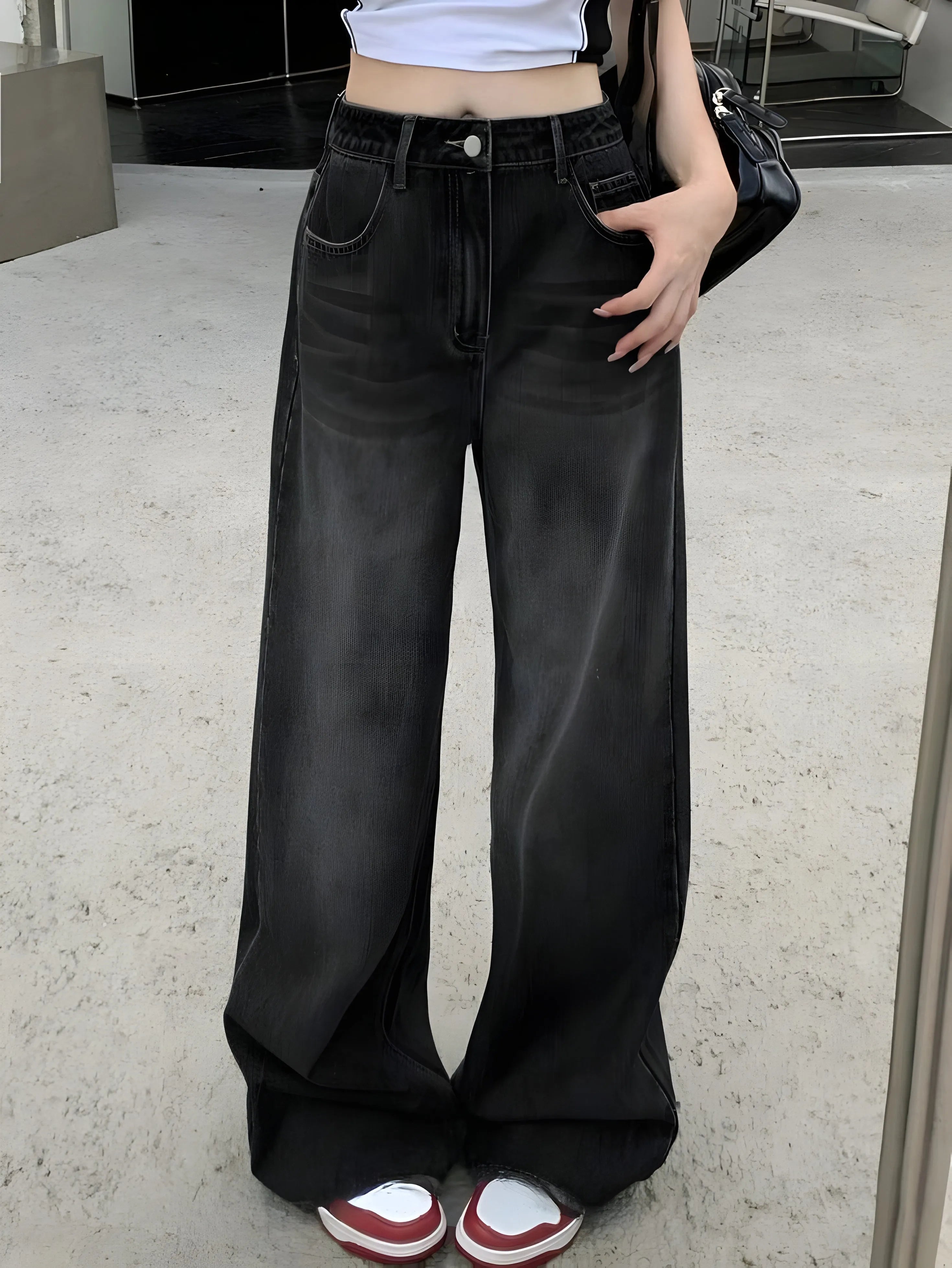 Person wearing black wide-leg jeans with a white background