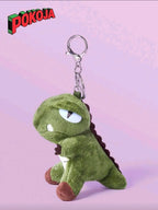 Green dinosaur plush keychain with Pokoja logo on a pink background
