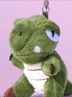 Green plush toy with a keychain on a pink background