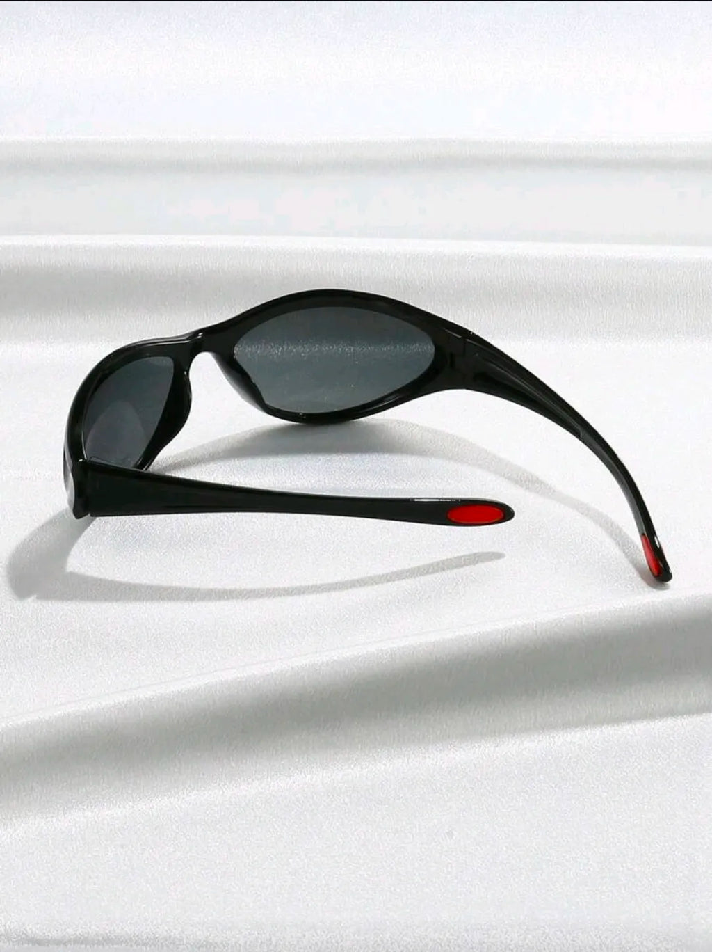 Black sunglasses with red accents on a white surface
