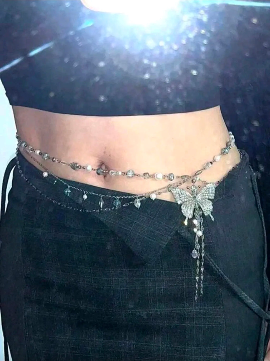 Decorative waist chain on a person wearing a black outfit.