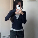 Person wearing a navy blue cardigan over a gray shirt, taking a mirror selfie.