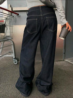 Person wearing dark blue jeans holding a cup in an indoor setting.
