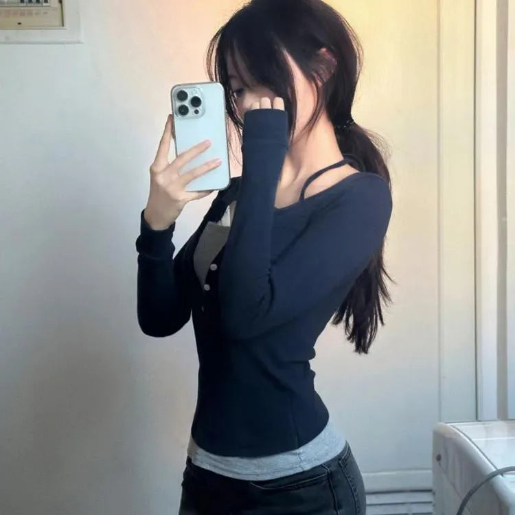 Woman taking a mirror selfie wearing a black long-sleeve top and gray pants.
