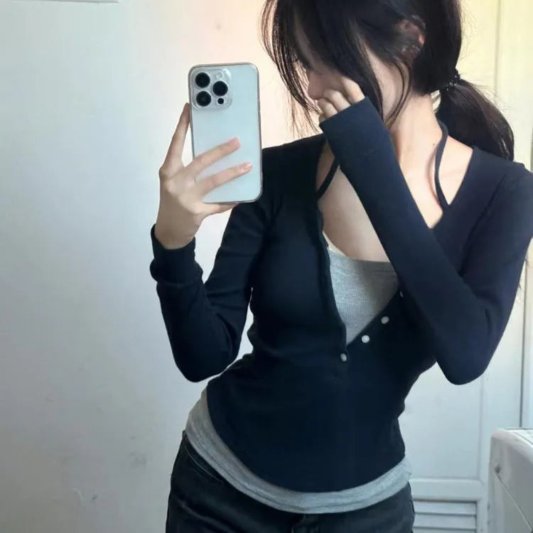 Person wearing a black cardigan over a gray top, holding a phone.