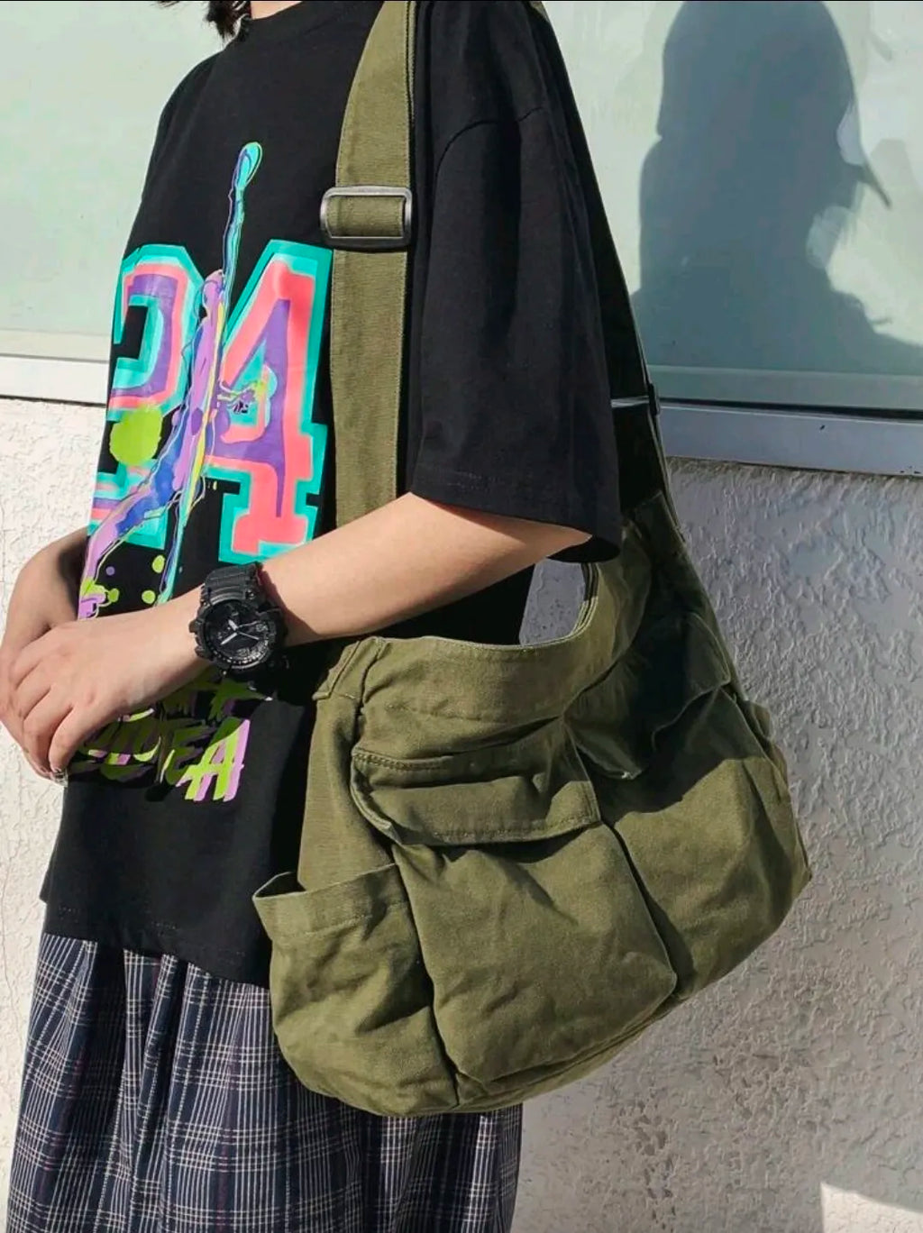 Person holding a green bag with a colorful 'D14' design on a black shirt.