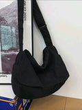 Black shoulder bag on a white surface with a blurred background
