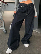 Person wearing wide-leg dark blue jeans with a blurred background