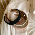 Set of three headbands in black, beige, and pink on a white fabric background