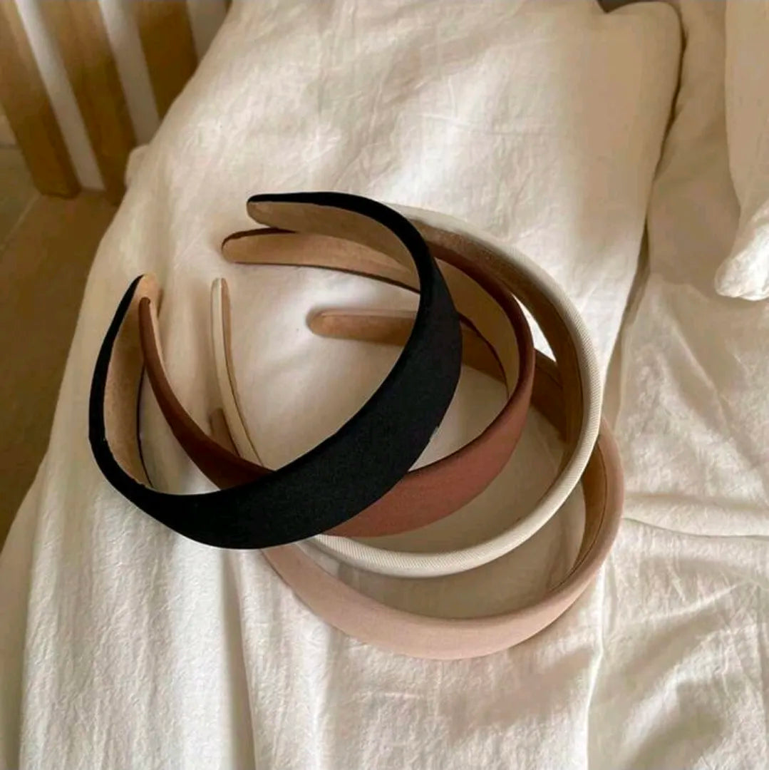 Set of three headbands in black, beige, and pink on a white fabric background