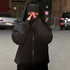 Person wearing a black hoodie and mask in an urban setting