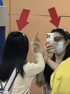 Two people taking a mirror selfie with red arrows on a cardboard box in the background.