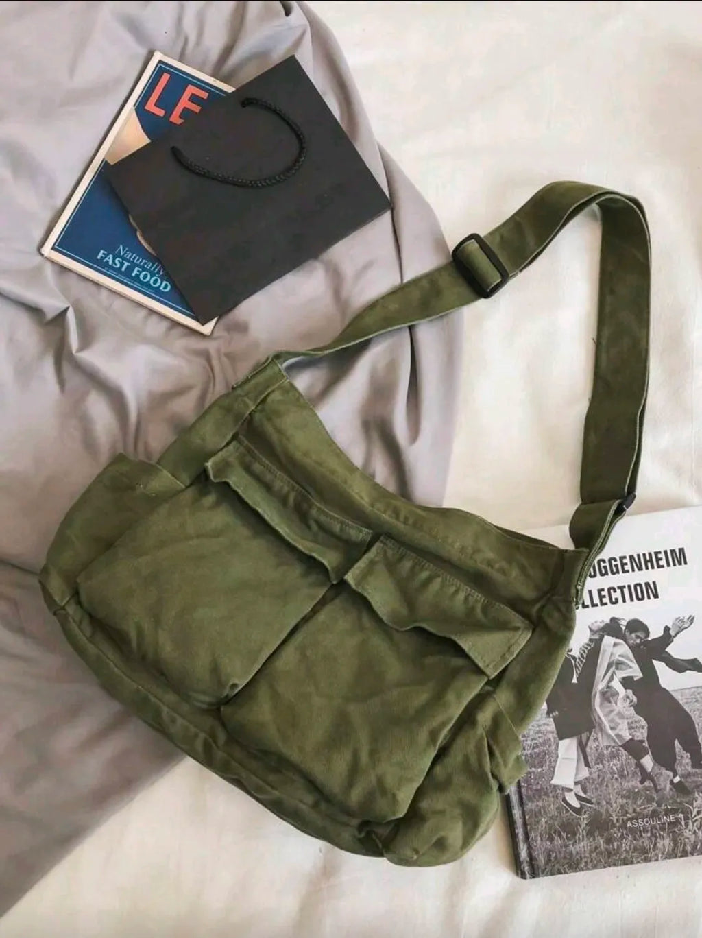Green shoulder bag on a bed with books underneath