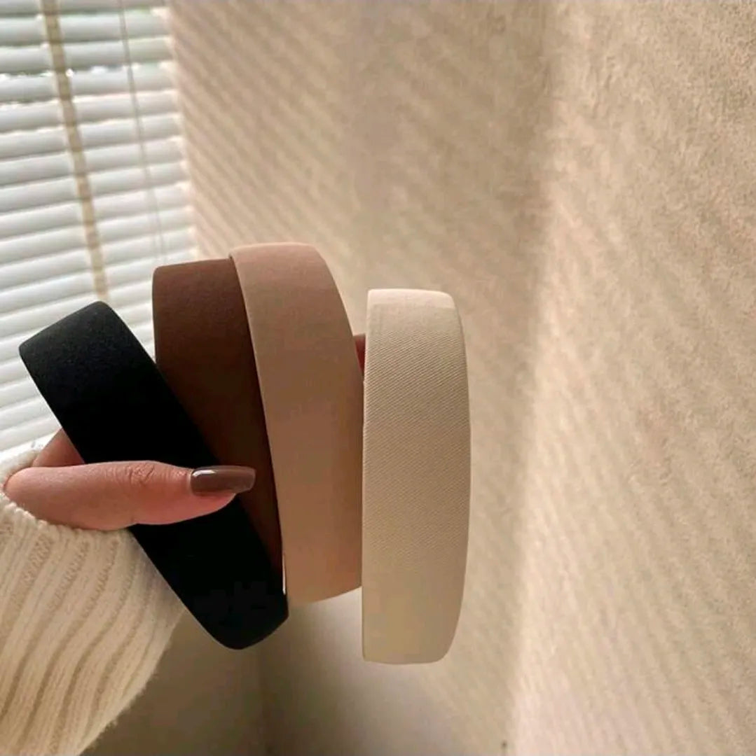 Three rolls of tape held by a hand against a neutral background